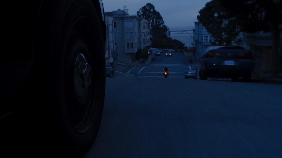 Bendix's car drives down the hill towards Amanita's motorcycle.
