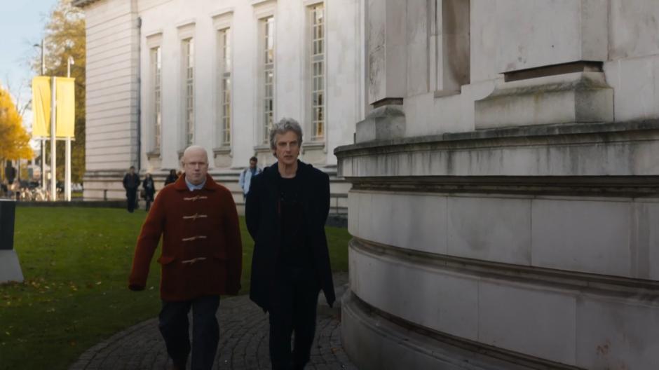 Nardole and the Doctor walk around the outside of the lecture hall back towards the Doctor's office.