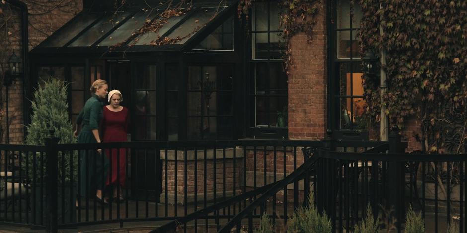 Serena leads Offred outside to Nick's home above the garage.