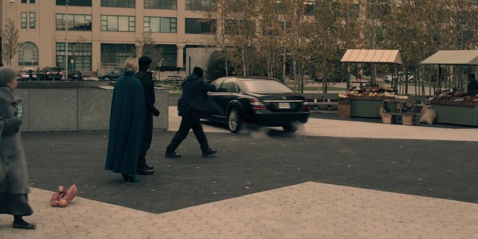 A guard runs up behind the car as Emily drives away quickly.