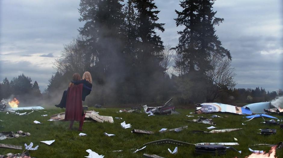 Kara lands in them middle of the crash site with Cat Grant in her arms.