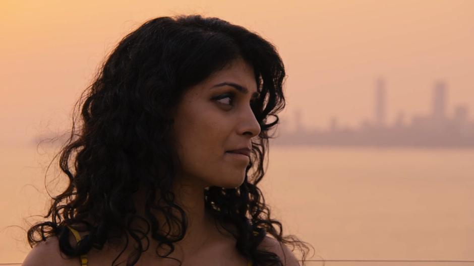 Kala looks at Wolfgang in front of the sunset lit skyline.