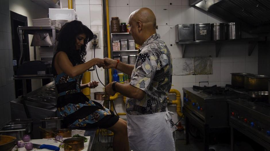 Sanyam hands Kala some of the sauce to sample in the restaurant kitchen.
