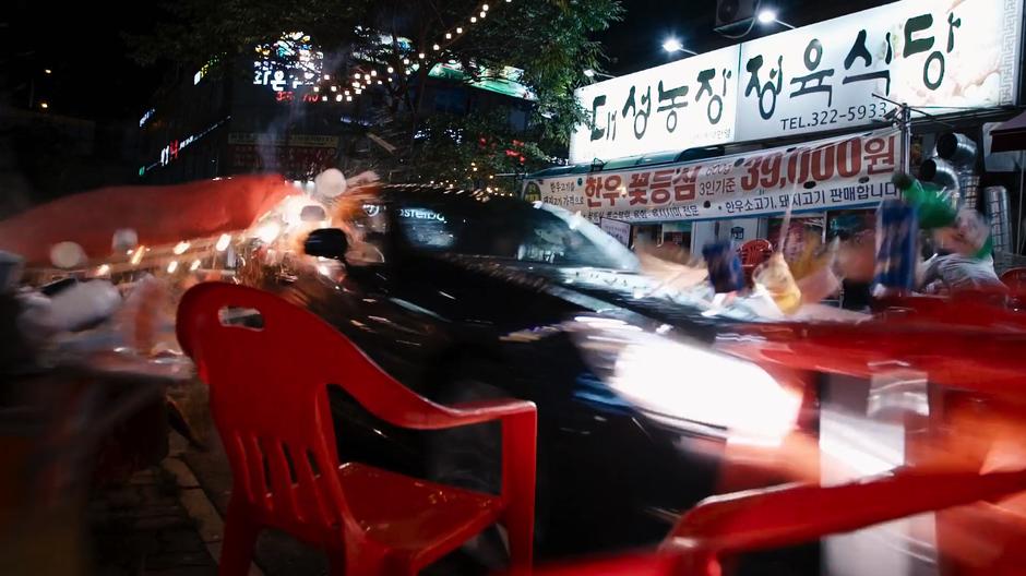 Joong-Ki crashes through tables set up along the street.