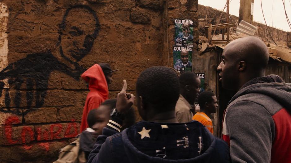 Jela points at the Courage graffiti to Capheus.