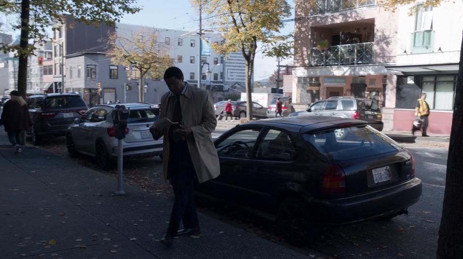 Coleman Baker looks at a newspaper as he walks from his car to his office.