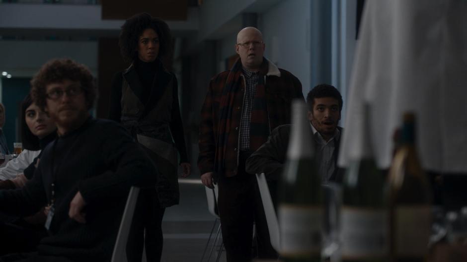 Bill and Nardole look on with concern as Nicolas addresses the assembled scientists.