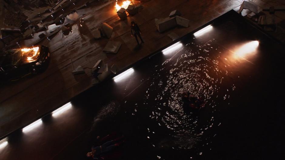 Alex holds Kara after she collapsed in the pond while Maggie looks on and Clark lies unconscious in the water.