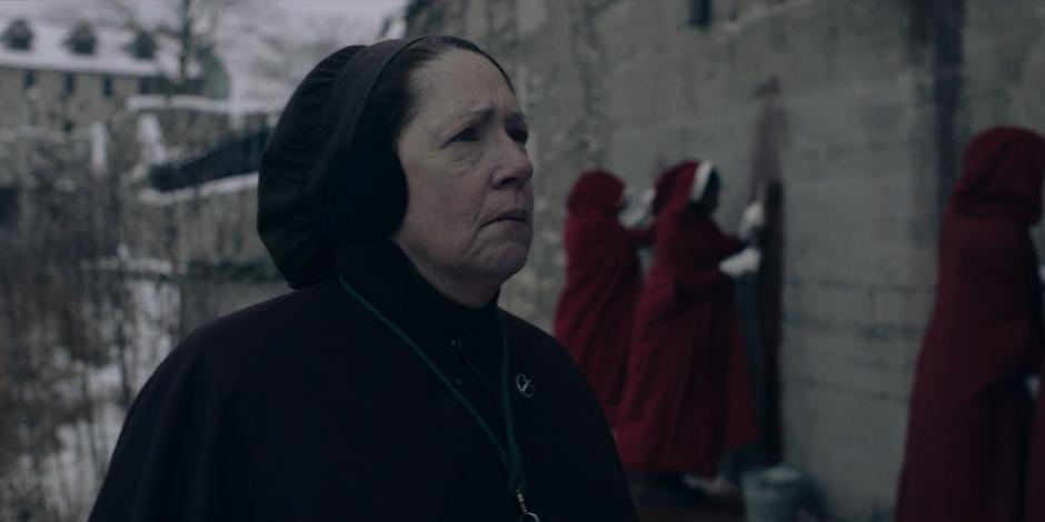 Aunt Lydia supervises the handmaids as they clean off the wall.