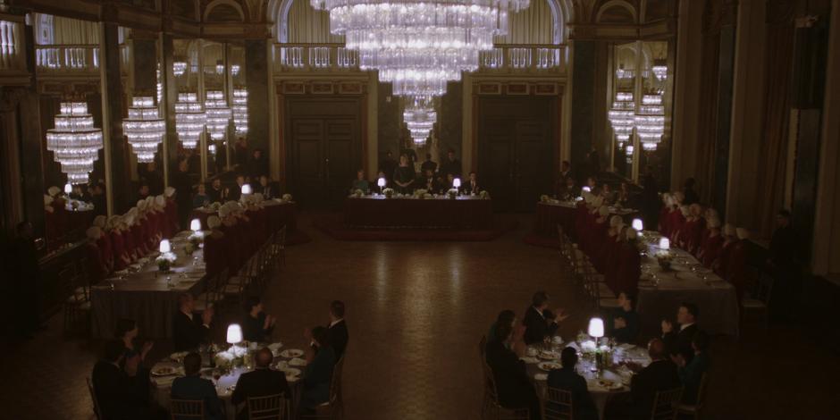 The handmaids stand up at their tables at Serena's request.