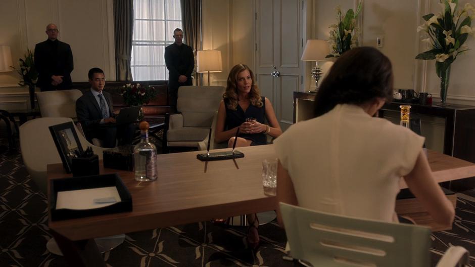 Charlotte sits at Bianca Ruiz's desk in her office while a tech reviews the status of Chet Ruiz's phone.