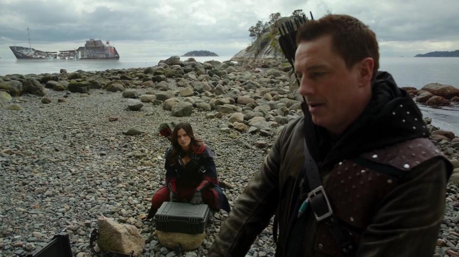 Nyssa prepares some supplies on the beach while talking with Merlyn.
