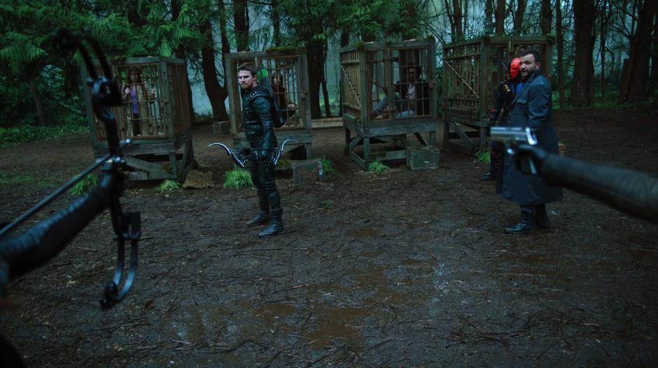 Talia's arrow and Evelyn's gun point at Oliver and his allies.