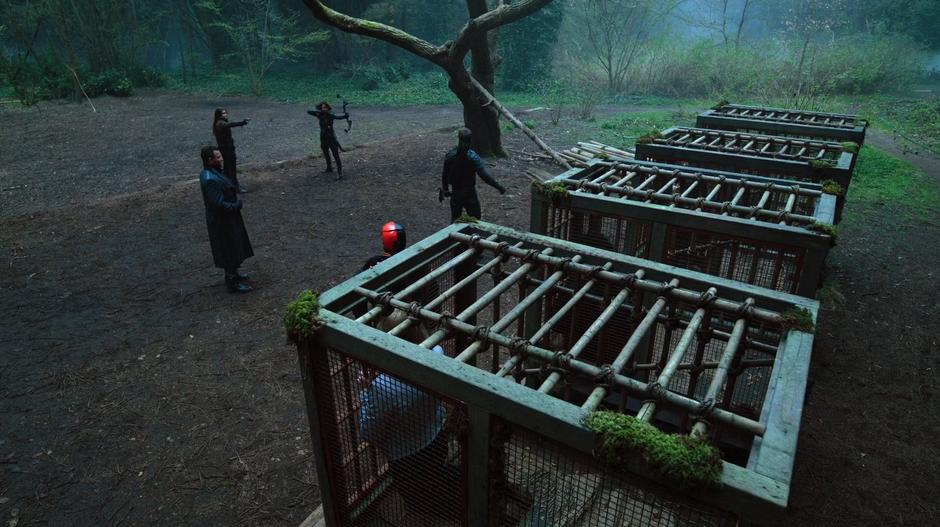 Evelyn Sharp and Talia al Ghul point their weapons at Oliver while Digger Harkness backs away from his supposed allies who are left standing in front of the cages.