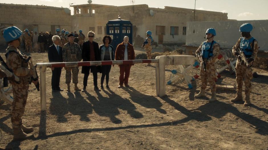 The Doctor, Bill, and Nardole stand at the United Nations barricade with the Secretary General and Colonel Brabbit.