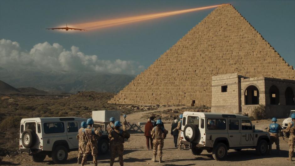 The group watches the pyramid lower the U.S. bomber down to the ground using its beam.