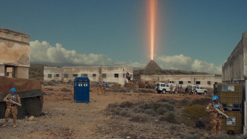 The Doctor, Nardole, and Bill run out to the cars with the military team while a beam shoots out of the top of the pyramid.