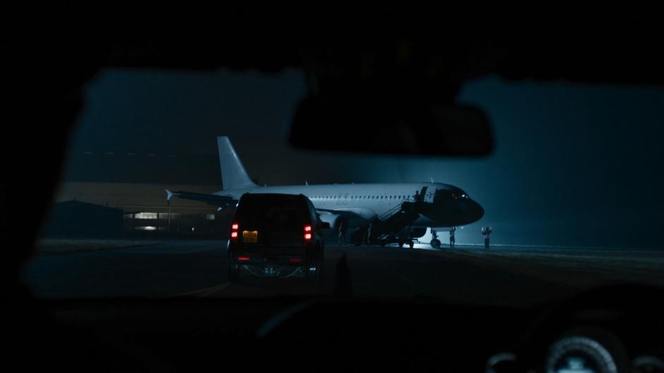 Bill is driven up to a waiting airplane at night.