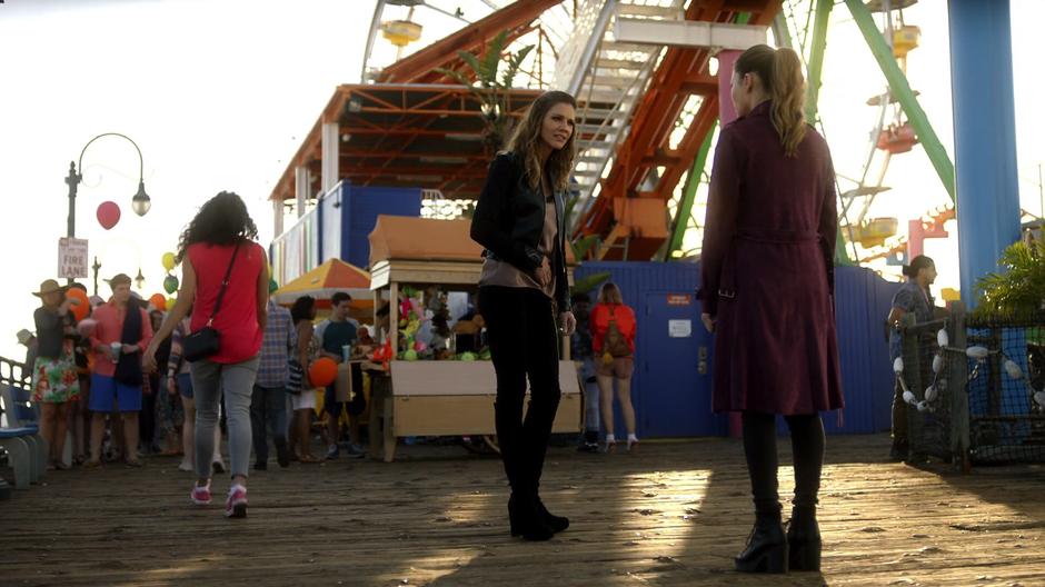 Charlotte talks with Chloe on the pier while holding her old stomach wound.