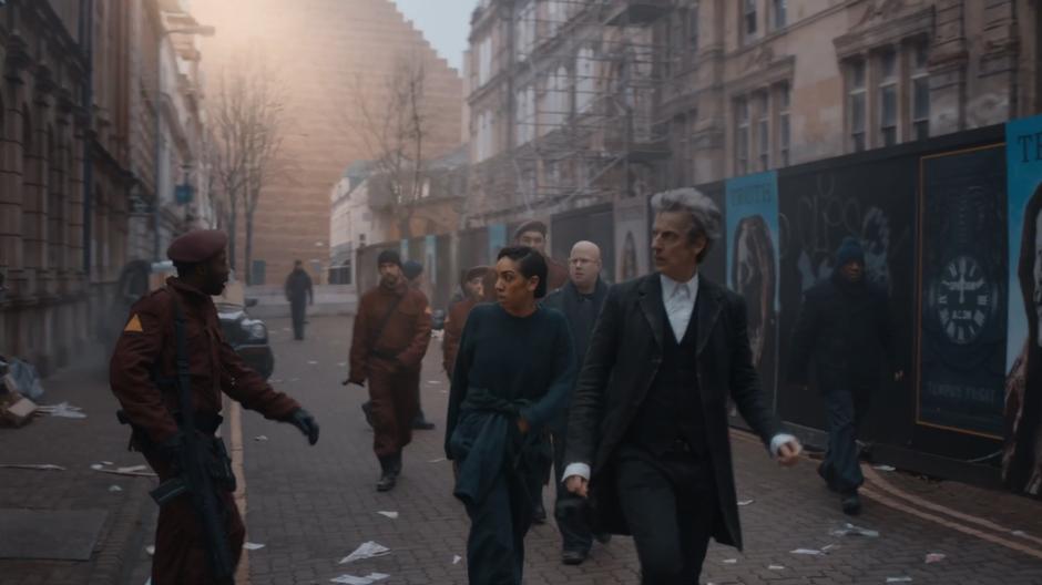 Bill, Nardole, and the Doctor walk down the street with the resistance members after defeating the monks.