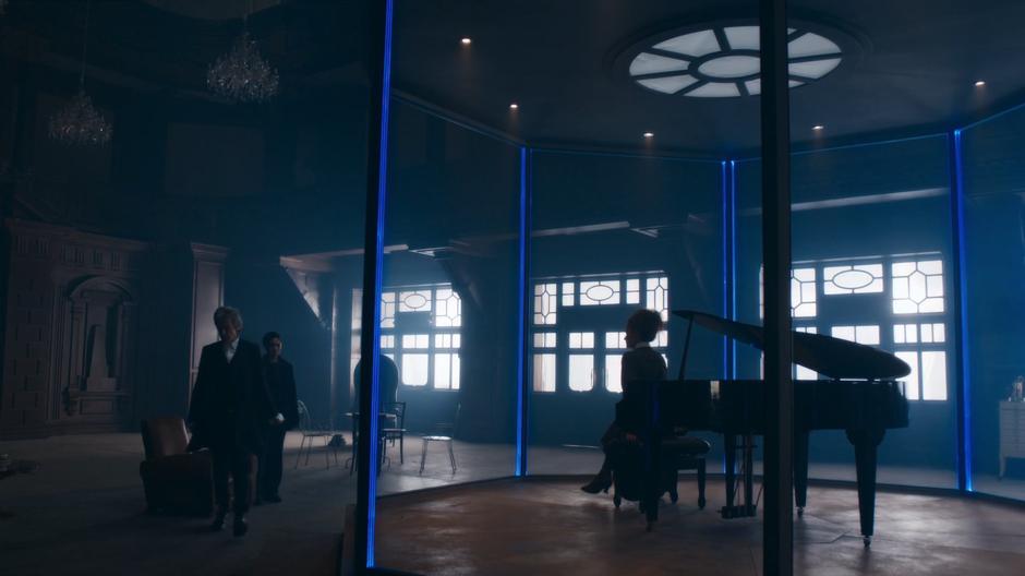 The Doctor stands up and walks around the room while Missy and Bill watch him.