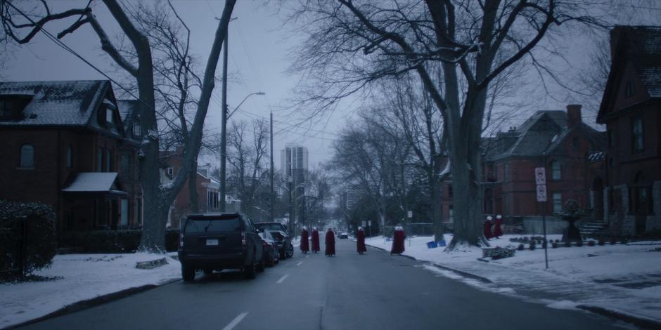 Offred walks down the center of the street as several handmaids turn off in different directions.
