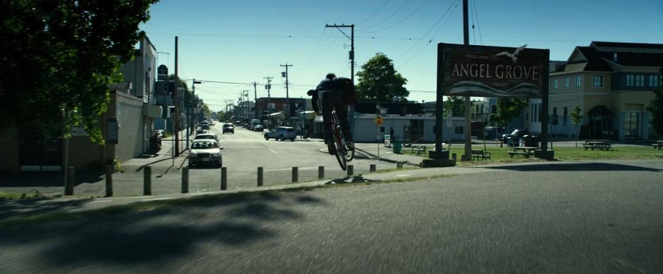 Jason jumps over the curb down past the sign.