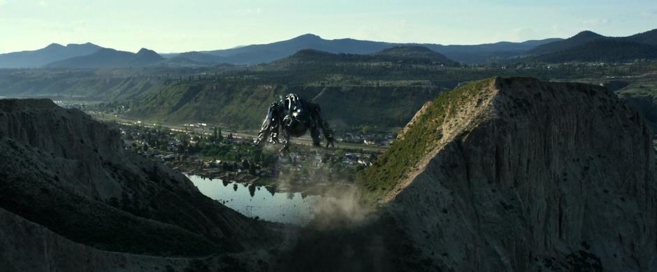 The black Zord jumps over a ridge towards the river.