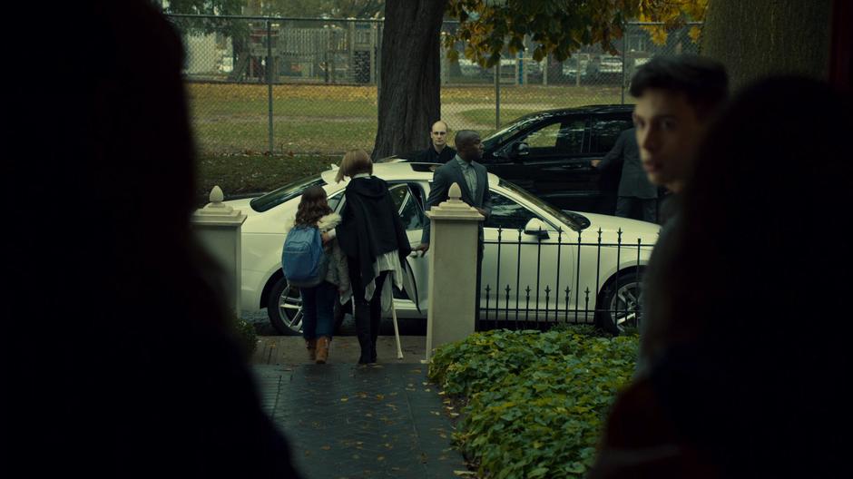 Rachel walks Kira to her car while Felix looks back at Siobhan and Sarah who are standing in the doorway.