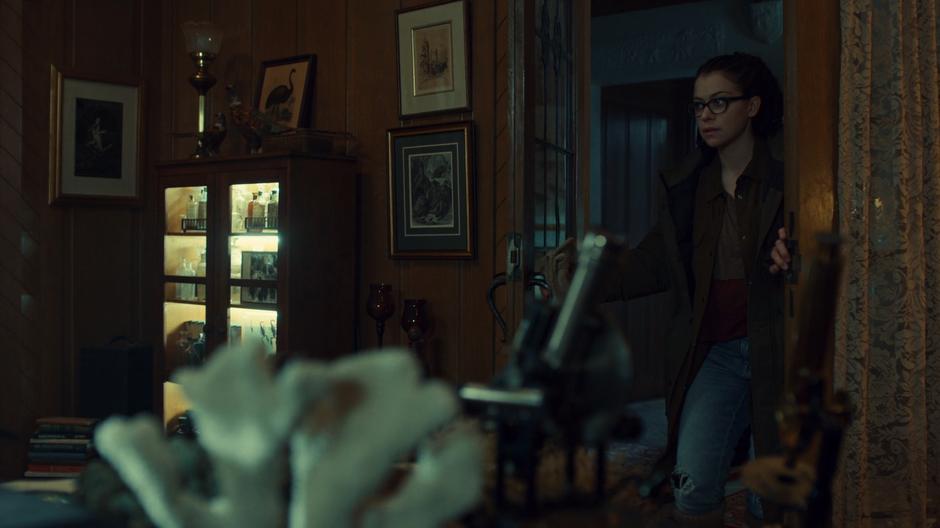 Cosima walks into the lounge of the house.