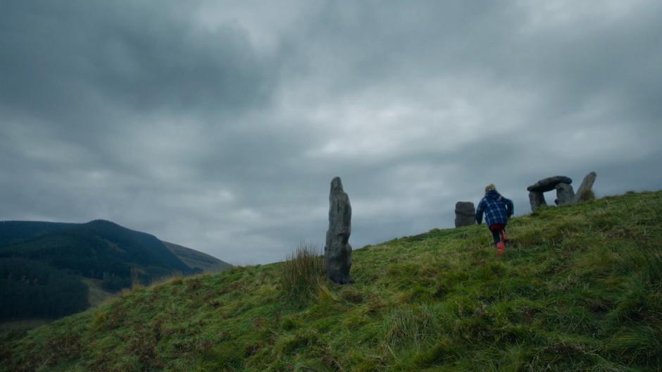 A young girl runs up the hill towards the ruins.