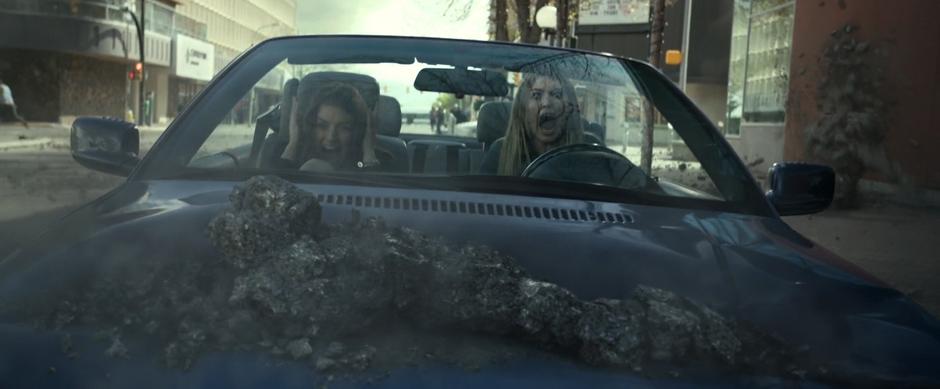Harper and Amanda scream as a piece of a Putty smashes into the hood of their car.