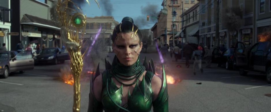 Rita walks down the street while people flee their cars and the shots from Kimberly's Zord hit the street behind her.