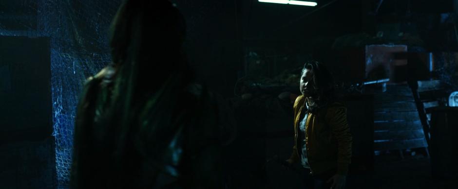 Trini threatens Rita in the middle of the warehouse.