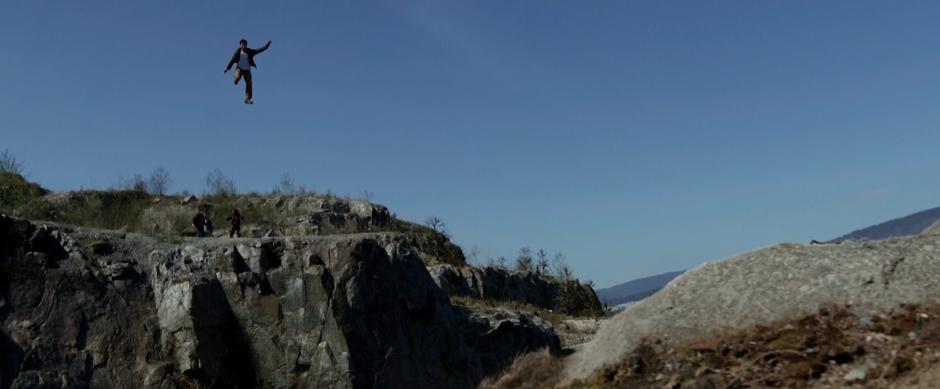 Zack leaps high above the chasm while Jason, Billy, and Kimberly watch from the far side.