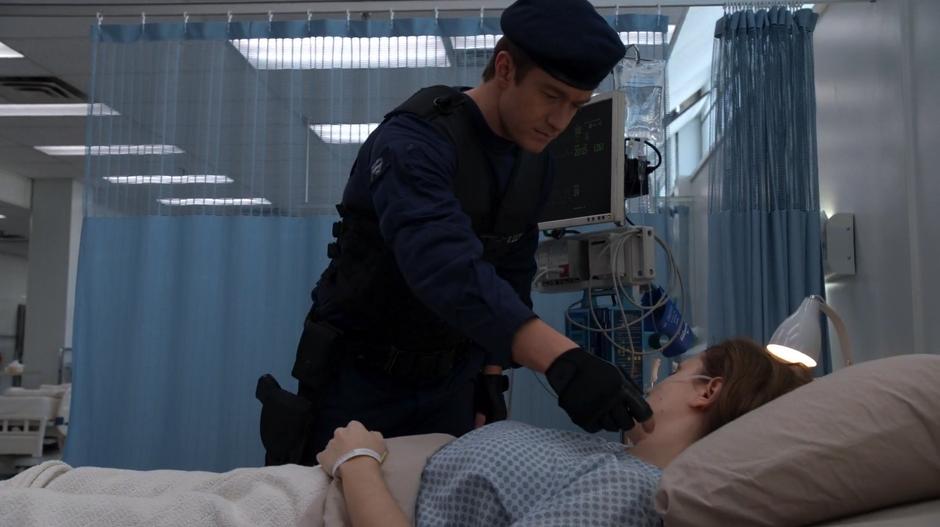Major reaches down to scratch a woman lying on a hospital bed.