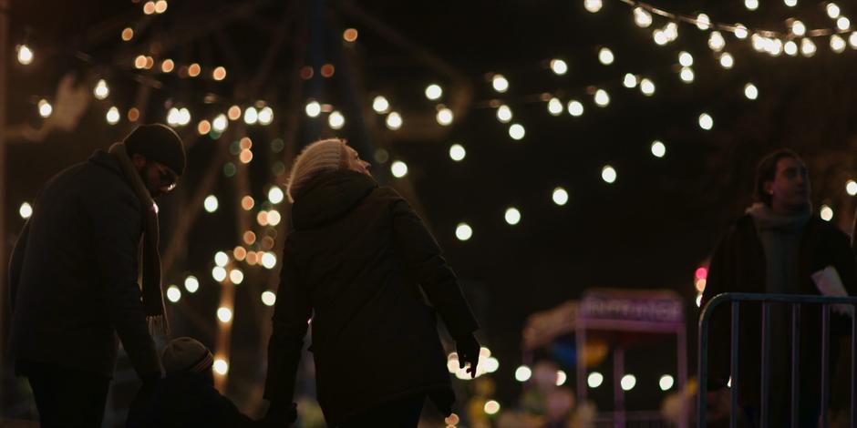 Luke and June hold Hannah's hand while they look around the carnival.