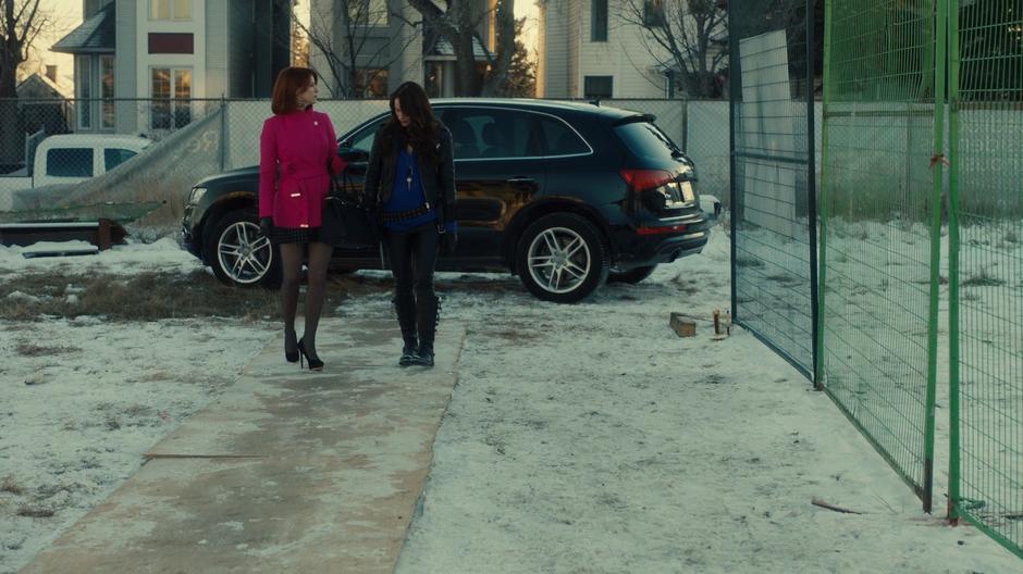 Mercedes and Wynonna walk down the path towards the building while chatting.