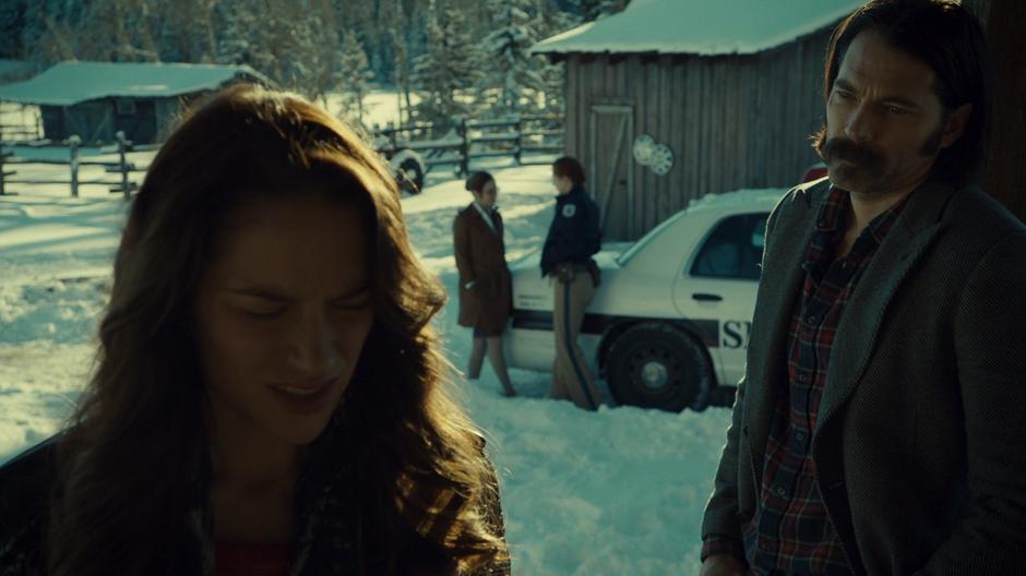 Wynonna stops on the porch to talk to Doc while Waverly and Nicole chat in the background by the police car.