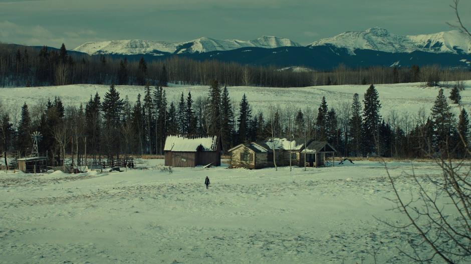 Wynonna walks across the snowy landscape from the house towards the hills.