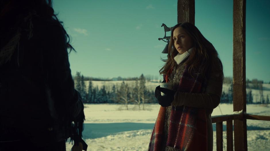 Waverly stands on the front porch with her mug while talking with Wynonna.