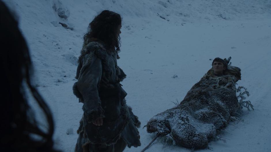 Meera looks back at Bran who is lying on the sled as he talks to Eddison Tollett.