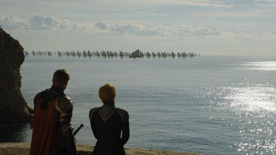 Jaime and Cersei look out from the wall to where the Iron Fleet is approaching the city.