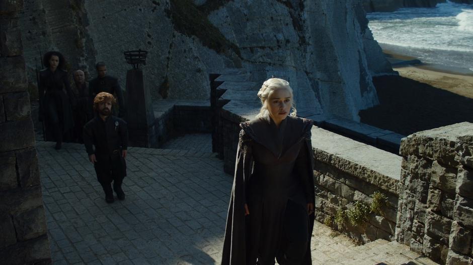 Daenerys walks up the steps to the gate followed by Tyrion, Missandei, Varys, and Grey Worm.