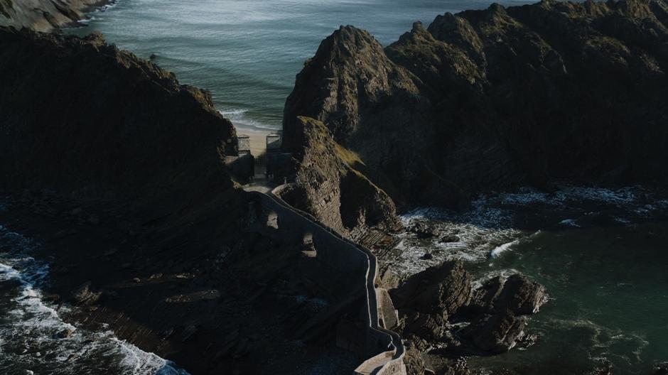 Daenerys and her party start across the causeway leading to the castle from the beach.