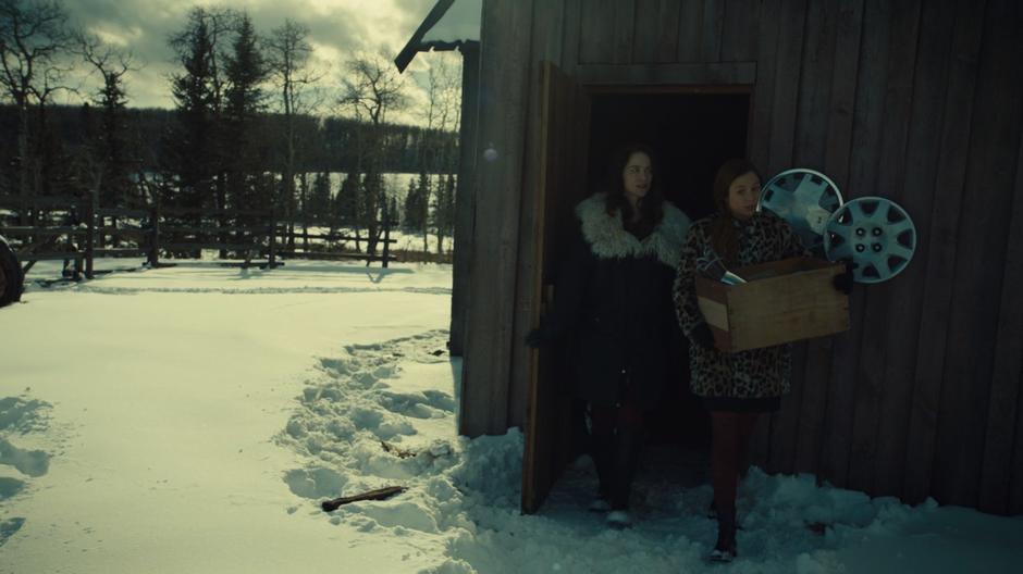 Waverly carries a box of stolen silver stuff out of the barn while Wynonna follows her.