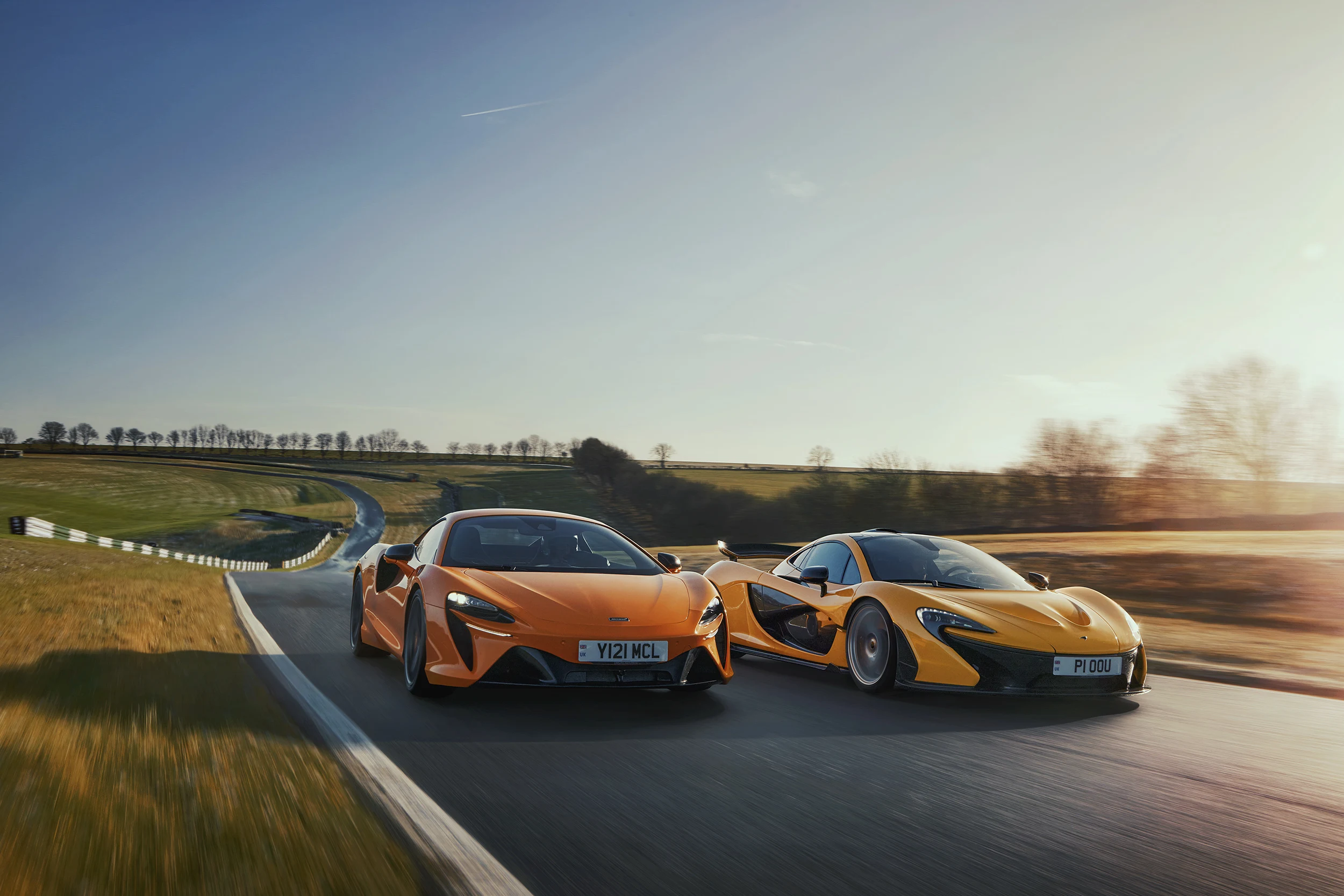 McLaren Boston 570S Orange and Yellow P1â„¢ driving around a race track side-by-side