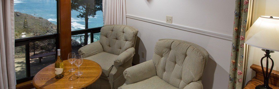 bottle of wine on small table near window overlooking ocean