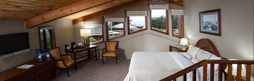 bed with table and chairs with vaulted ceiling and windows