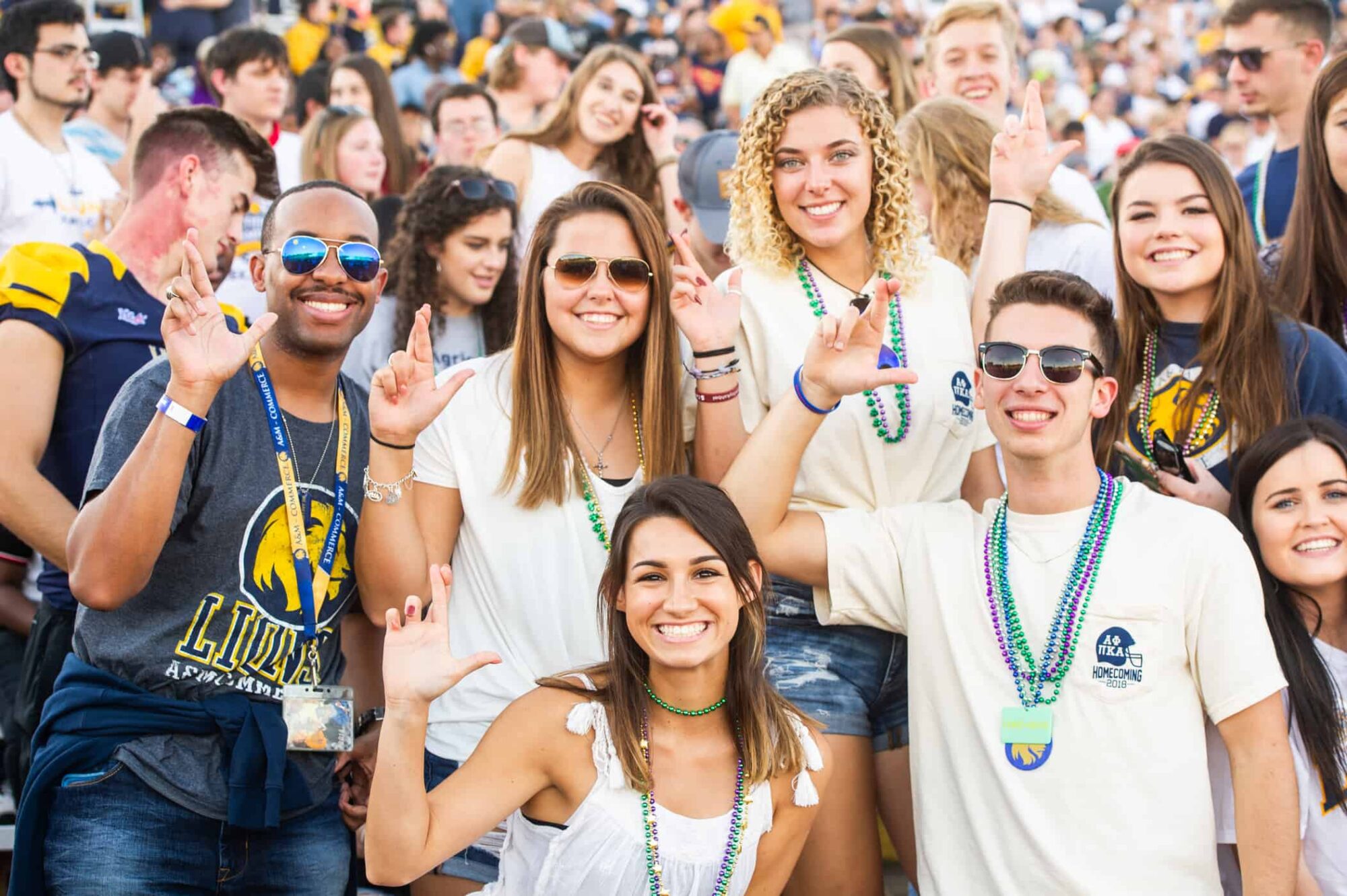 students during the homecoming football game making the lion sign.